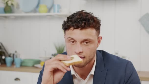 Rizado hombre raro con ojos marrones mira a la cámara y come sándwiches con monedas — Vídeos de Stock