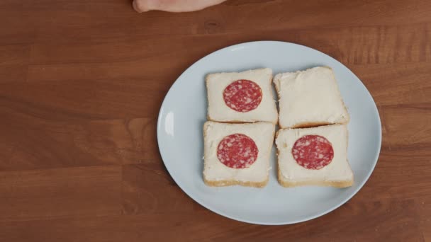 Мужская рука берет кусок сосиски и кладет его на сэндвич — стоковое видео