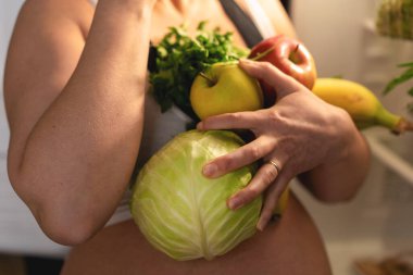 Hamile kadınların ellerinde taze sebzeler ve meyveler. Sebzeler ve meyveler kapanıyor..