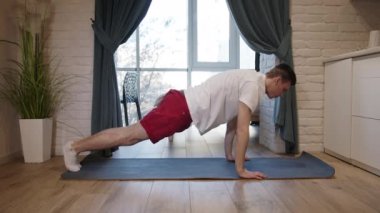 Genç ve yakışıklı bir adam antrenman yapıyor ve vücudunu şekle sokuyor. Her sabah esneme ve sporla başlar.