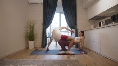 Genç çift evde yoga yapıyor. Genç çift bunu birlikte öğrendikleri için çok heyecanlı.