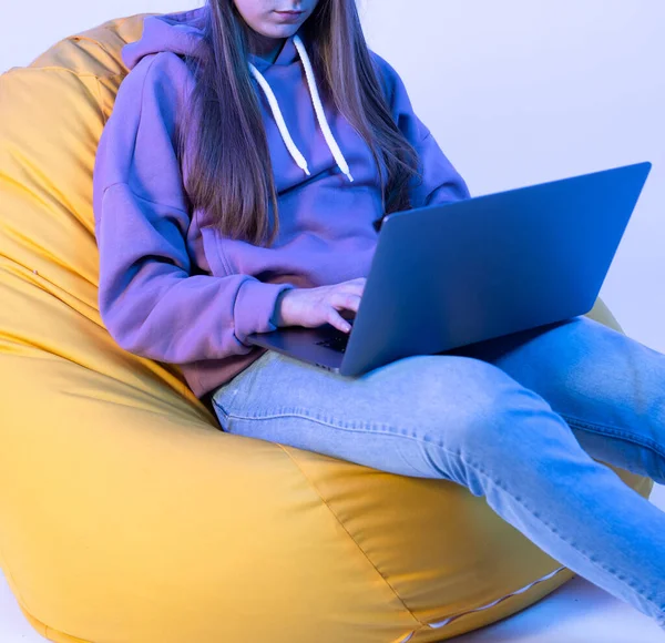 Dizüstü bilgisayara bakıp el ele tutuşan bir kız. Kot pantolon ve pembe ceket giymişti. Fotoğraf ayrıntıları.