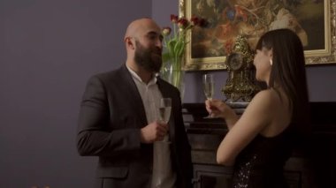 Zarif bir gece elbisesi giymiş erkek ve kadın bir kadeh şampanya içerken birbirleriyle konuşuyorlar. 4k video