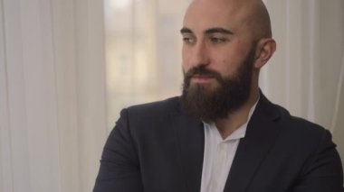 Siyah takım elbiseli, güzel sakallı genç bir adamın şık gülümsemesi. 4k video