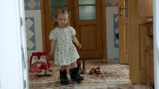 Funny little girl in a short dress shyly enters the room — Stock Video