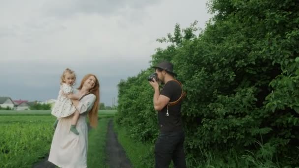 Vater fotografiert seine Frau und Tochter mit einer Kamera im Wald. Mutter und tochter posieren für die kamera. — Stockvideo