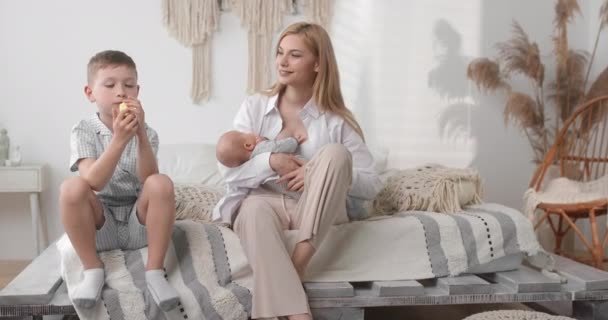 Mom watches her son eat. The child appetizingly eats fruit. Young family. — Stock video