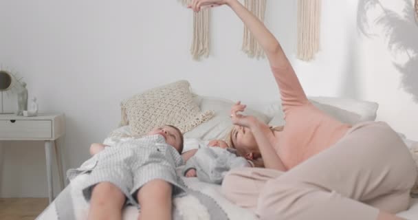 Mom takes a selfie with her children in bed. Photo for memory at home with children. — Stock Video