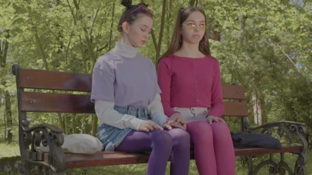Quarrel of two lesbians in the park. Two teenage girls on a park bench. — Vídeos de Stock