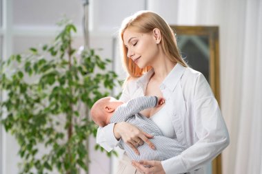 Bebek annesinin kollarında uyuyakaldı. Anne bebeği kucağında tutuyor ve bebeğe gülümsüyor. Anne sevgisi..