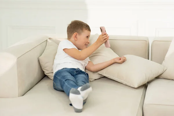 The boy holds the phone and shows his mother something on the phone. Happy little boy.