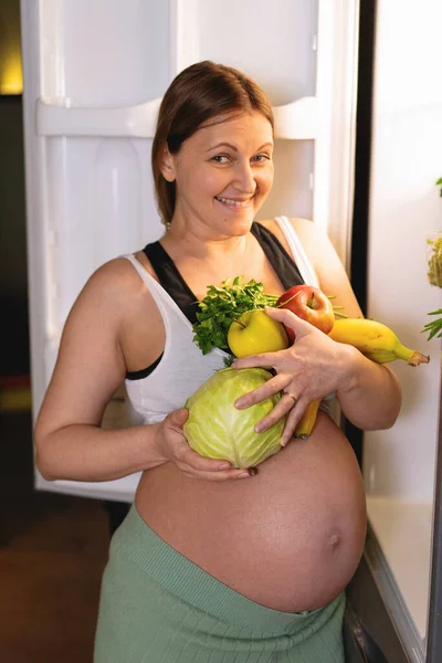 Mujer Embarazada Está Sinceramente Sonriendo Sosteniendo Una Gran Cantidad Verduras —  Fotos de Stock