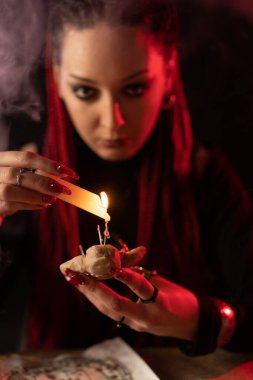 Melted wax from a candle falls on a voodoo doll in the hands of a witch. Divination with the help of black magic.