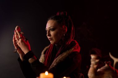 The witch holds a voodoo doll and casts a spell on it. Fear of being cursed. Details for divination.