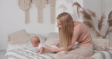 Anne, çocuğun fiziksel durumunu iyileştirmek için her sabah bebekle egzersiz yapar. Yatay video.
