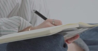 Kız rüyalarını bir deftere yazıyor. Kız bir defterde kalemle yakın çekim yazıyor. Yatay video.