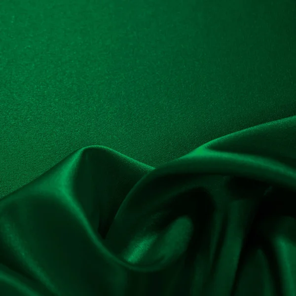     Koyu yeşil ipek kadife. Güzel yumuşak dalgalı kıvrımlar parlak kumaş üzerinde. Tasarım için kopyalama alanı olan zarif bir arkaplan. Noel, tatil, şenlik.                           