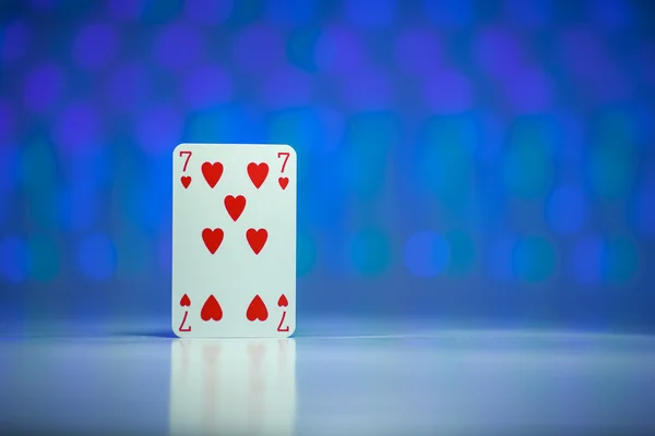 Rotes Herz sieben Spielkarte mit blauem verschwommenen Kreis Hintergrund Stockbild