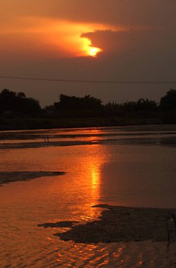Tambaksegoro köyü, Sidoarjo, Endonezya çevresindeki göletin kenarında güzel bir günbatımı.