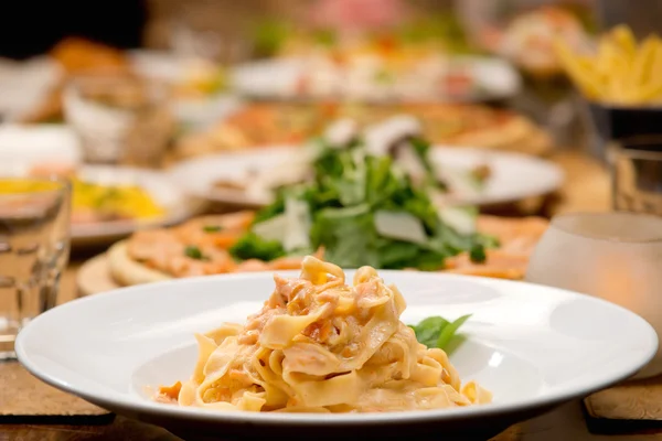 Table of pasta and other food plates — Stock Photo, Image