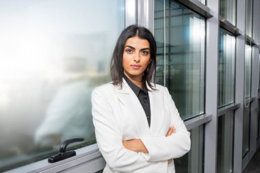 Modern bir ofiste kameraya bakan neşeli bir iş kadınının portresi.