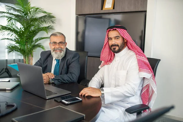 オフィスでのビジネスミーティング 成熟したビジネスマンとビジネス会話をし ラップトップで作業するアラビアのビジネスマン — ストック写真