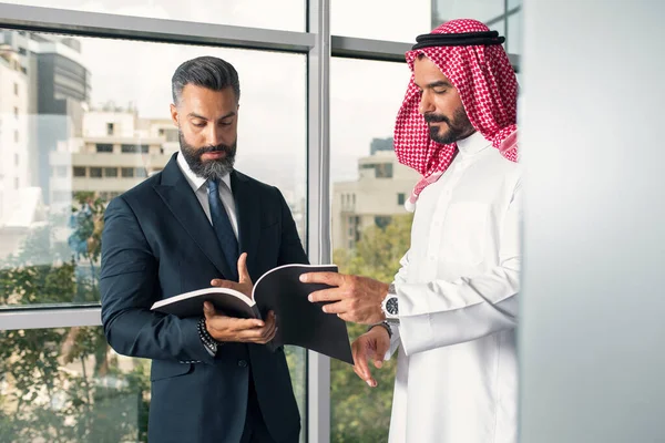 阿拉伯商人与外国商人讨论在现代办公室工作 图库图片