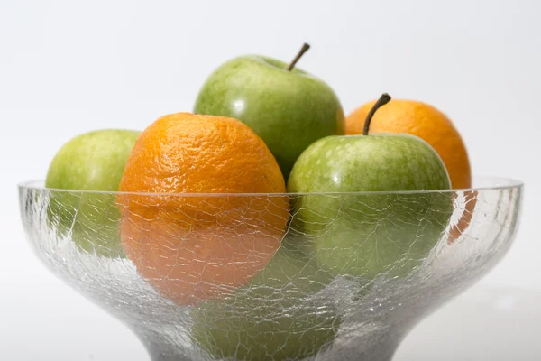 Apples and oranges in glass bowl — Stock Photo, Image