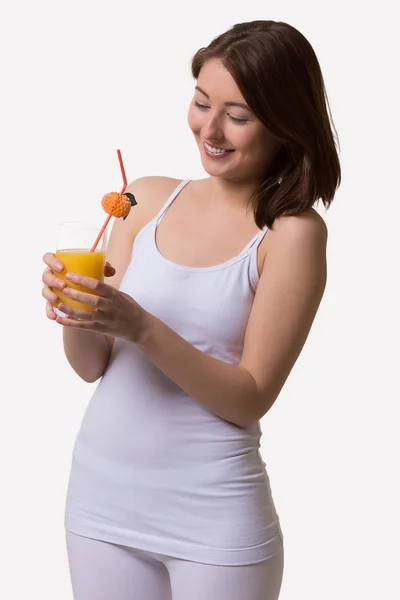 Jonge vrouw lachend kijkt naar een glas sinaasappelsap. — Stockfoto