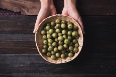 Vahşi Hint bektaşi üzümü ya da amla bir bambu sepetinde ahşap zemin üzerinde, Asya 'da meyve ağacı çeşitli mutfaklarda, bitkisel ilaçlarda ve zengin C vitaminlerinde kullanılır.
