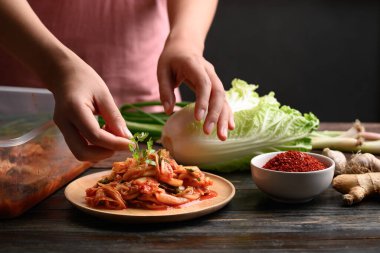 Kadın eli kişniş yapraklı ahşap tabak süslemeli kimchi lahana, ev yapımı Kore yemeği.