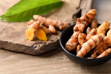 Ahşap arka planda bir kasede taze zerdeçal, Asya yemeklerinde besin maddeleri ve güzellik merkezinde ve bitkisel ilaçlarda kullanılır.