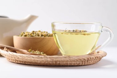 Papatya çayı ve kurumuş papatya çiçekleri beyaz arka planda bir kasede, sağlıklı bitki çayı.