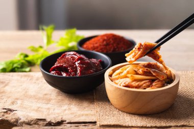 Kore kimchi lahanası yemek için gochujang (kırmızı biber ezmesi) ve ahşap arka planda kırmızı biber tozu kullanılır.