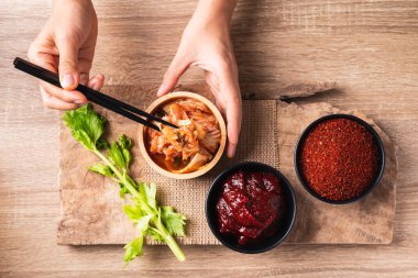 Kore kimchi lahanası gochujang (kırmızı biber ezmesi) ve ahşap arka planda kırmızı biber tozu kullanarak yemek, masa üstü görünümü