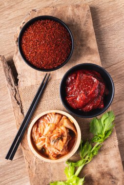 Gochujang (kırmızı biber ezmesi) ve ahşap zemin üzerinde kırmızı biber tozu ile Kore kimchi lahanası, masa üstü görünümü