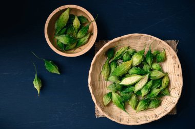 Taze organik acı kabak ya da bambu sepetinde koyu arkaplan, gıda malzemeleri ve bitkisel ilaçlar, üst görünüm.
