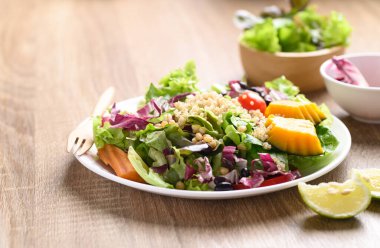 Tahta zemin üzerinde kinoa salatası olan taze organik sebzeler sağlıklı vegan yemekleri.