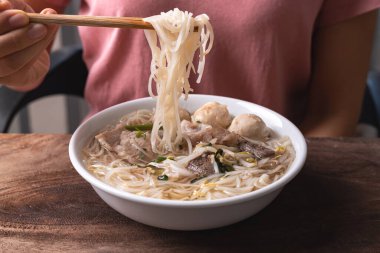 Bir kasede domuz etli erişte çorbası ve yemek çubuğu ve Tayland eriştesi çorbası.