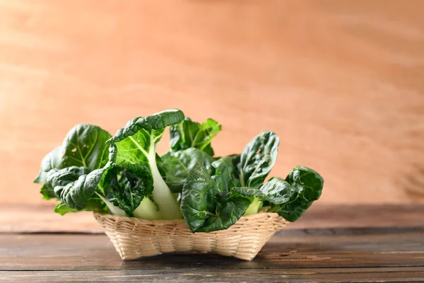 Tahta arka planda bambu sepeti içinde taze organik Bok Choy veya Pak Choi (Çin lahanası)