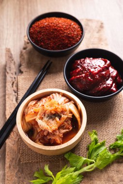 Gochujang (kırmızı biber ezmesi) ve ahşap arka planda kırmızı biber tozu ile Kore kimçili lahana.