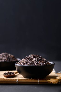 Tayland mor glutinous pilavı siyah arka planda kasede, organik ve sağlıklı yiyecekler.