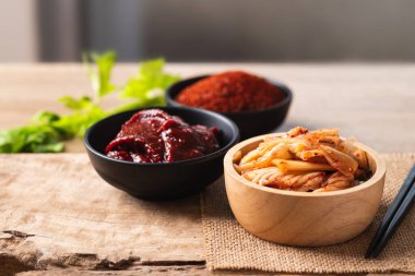 Gochujang (kırmızı biber ezmesi) ve ahşap arka planda kırmızı biber tozu ile Kore kimçili lahana.