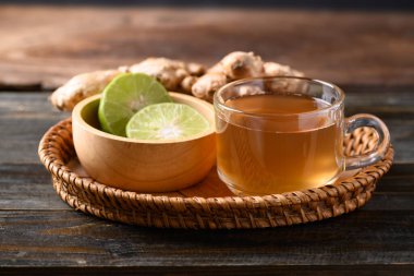 Tahta arka planda limonlu zencefilli çay, sağlıklı bitkisel içecek.