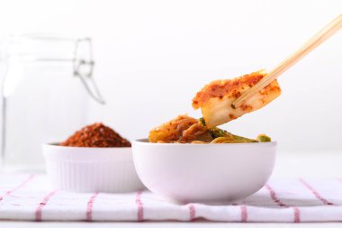 Beyaz arka planda yemek çubuklarıyla yemek yiyen kimçi lahanası, Kore ev yapımı mayalanmış meze.