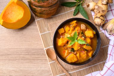 Tahta masadaki domuz etli baharatlı balkabağı çorbası.