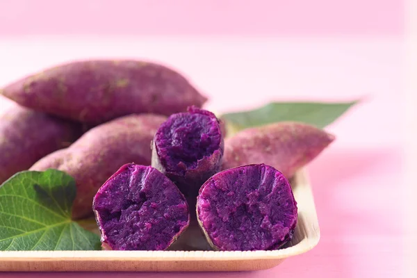 Purple sweet potatoes on natural plate with pink background ready to eating