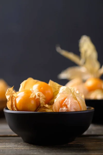 Cape gooseberry or golden berry (Physalis peruviana) in black bowl on wooden background, Healthy tropical fruit
