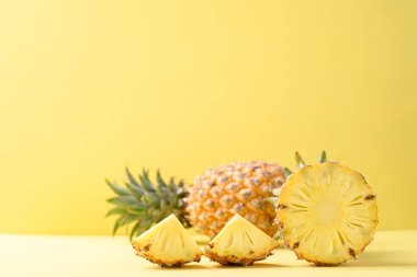 Sarı arka planda dilimlenmiş ananas meyvesi, tropikal meyve.