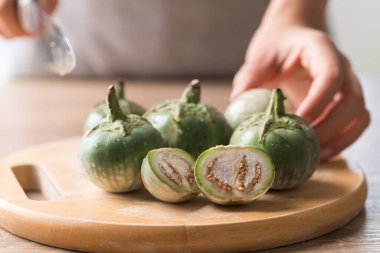 Tahta üzerinde el ele tutuşan ve Tayland patlıcanı kesen Tayland yemeği pişirmeye hazır olun.